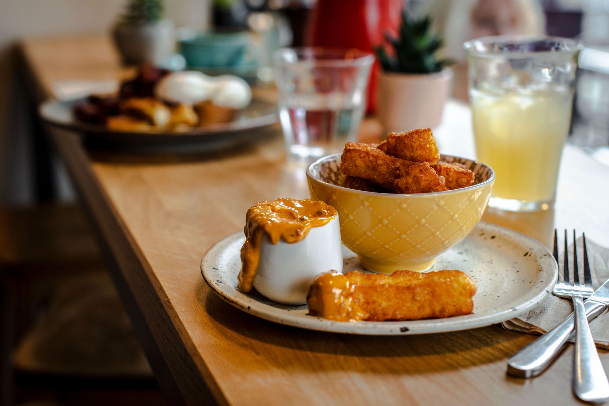 Halloumi tries in a bowl on a wooden counter with knife and fork