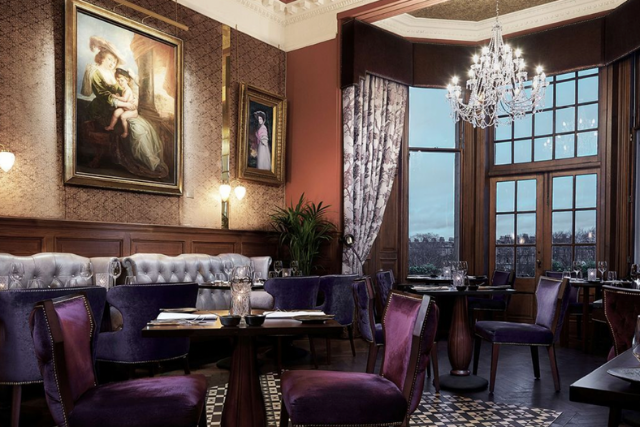 Wood panelled dining room with purple velvet chairs and a bay window