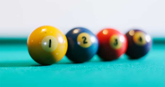 four pool balls in a row on green felt