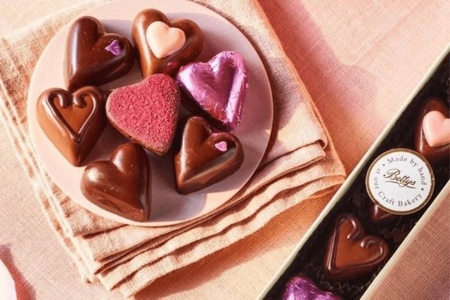 Chocolate hearts from Bettys on a plate and in a display box, laid out on a pink tablecloth