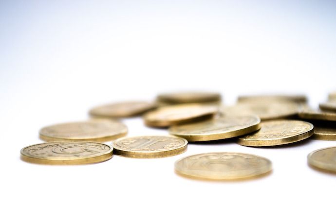 A bunch of gold coins lying flat on a white surface.