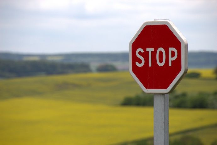 wooden 'stop' sign against a background of rolling green hills