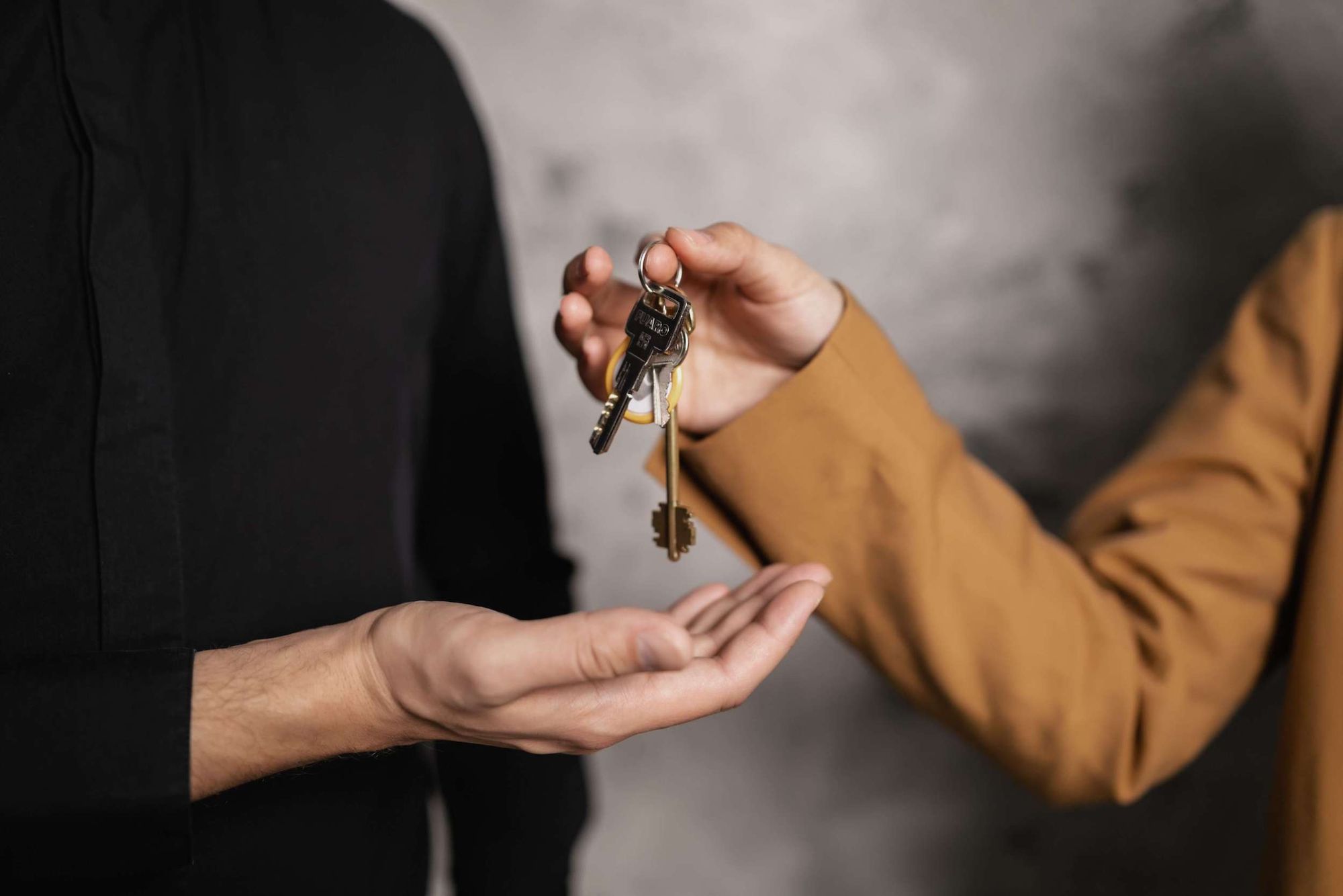 Close up of woman's hands putting keys into a man's open palm.