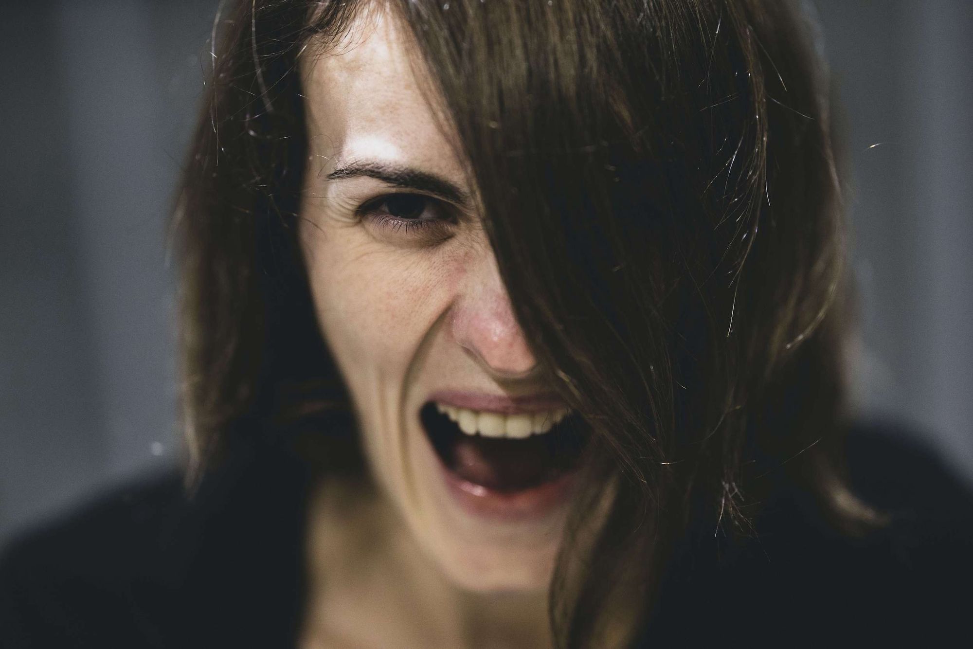 Close-up of woman screaming with long hair covering one side of her face