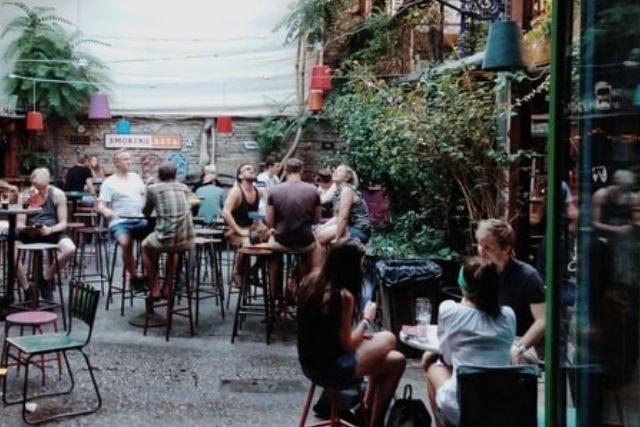 People sitting outside in a colourful brick-walled courtyard