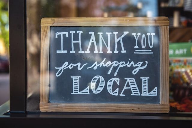 Blackboard sign with 'Thank you for shopping local' written in white chalk