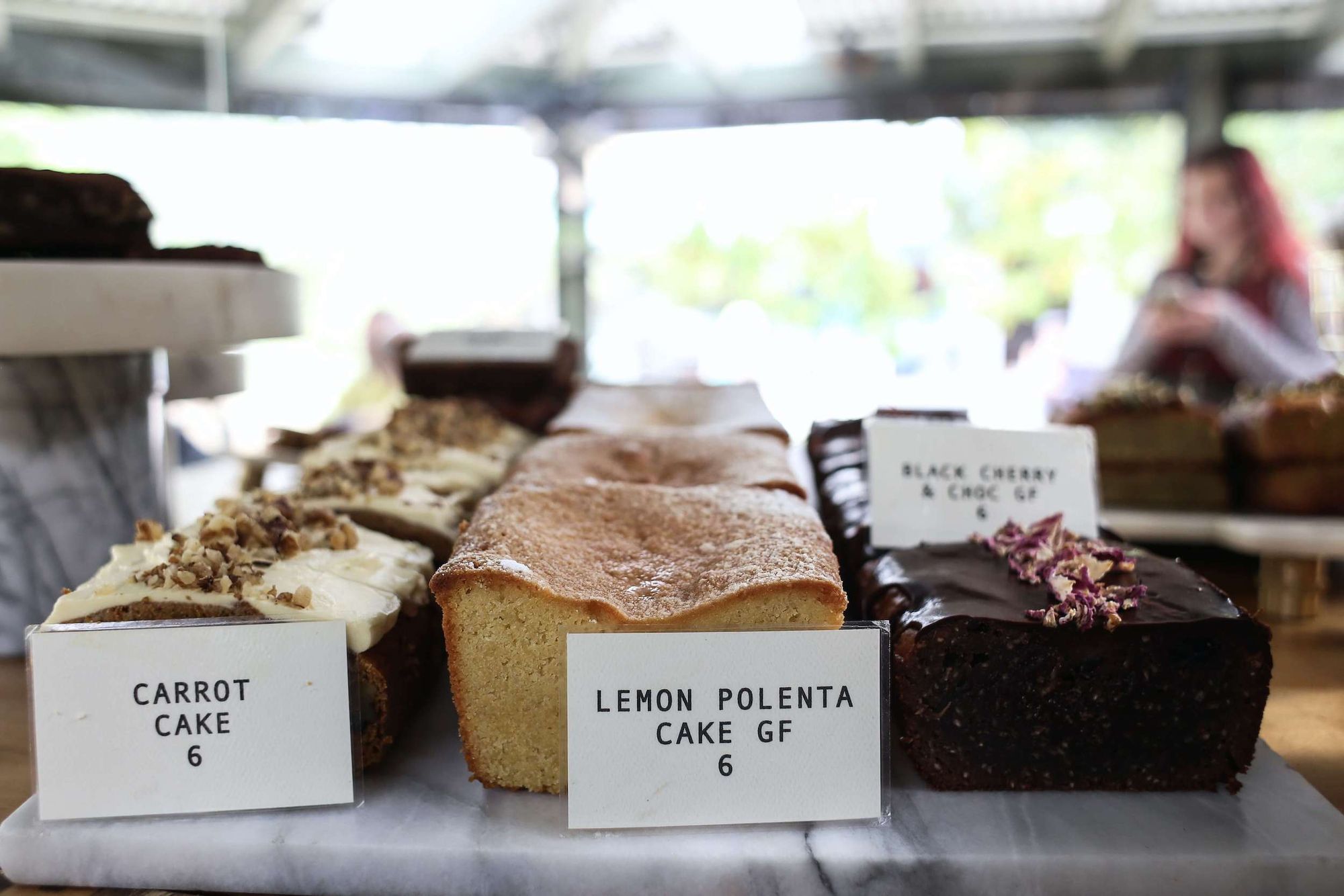 A variety of cakes on a slab: carrot cake, lemon polenta, black cherry and chocolate.