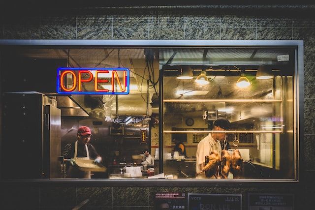 Through the window of an Asian restaurant at night with a neon'Open' sign lit up