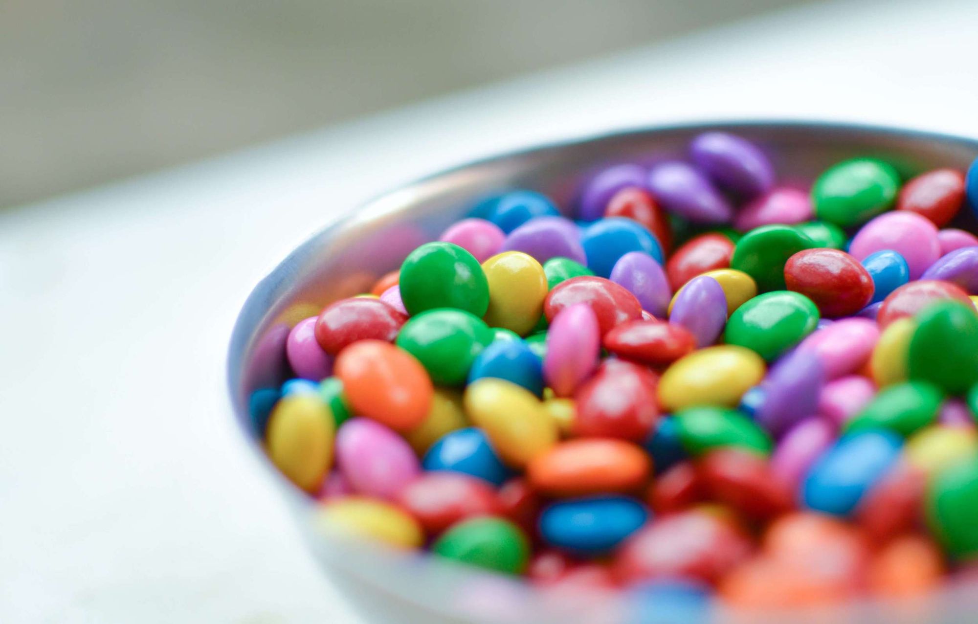 Close-up photo of a large ceramic bowl of brightly coloured M&Ms.