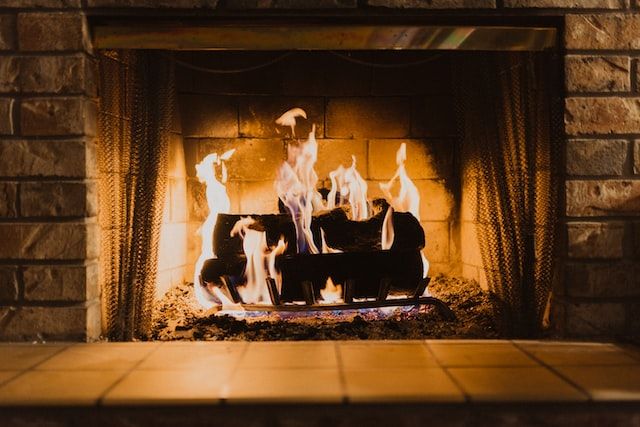 Fire burning in a brick fireplace, with flames leaping from the logs.