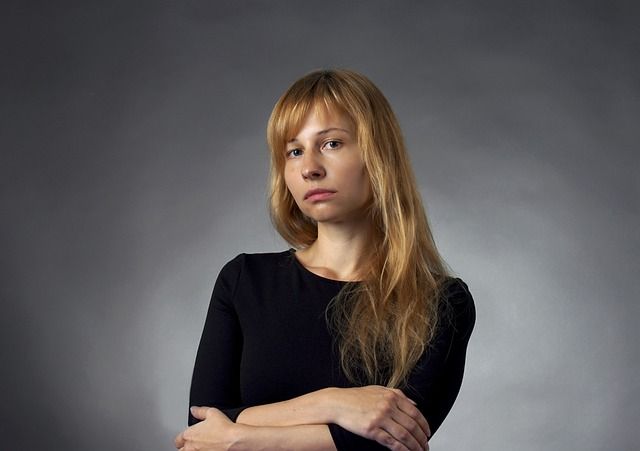 Annoyed-looking woman staring at the camera, against a plain grey background.