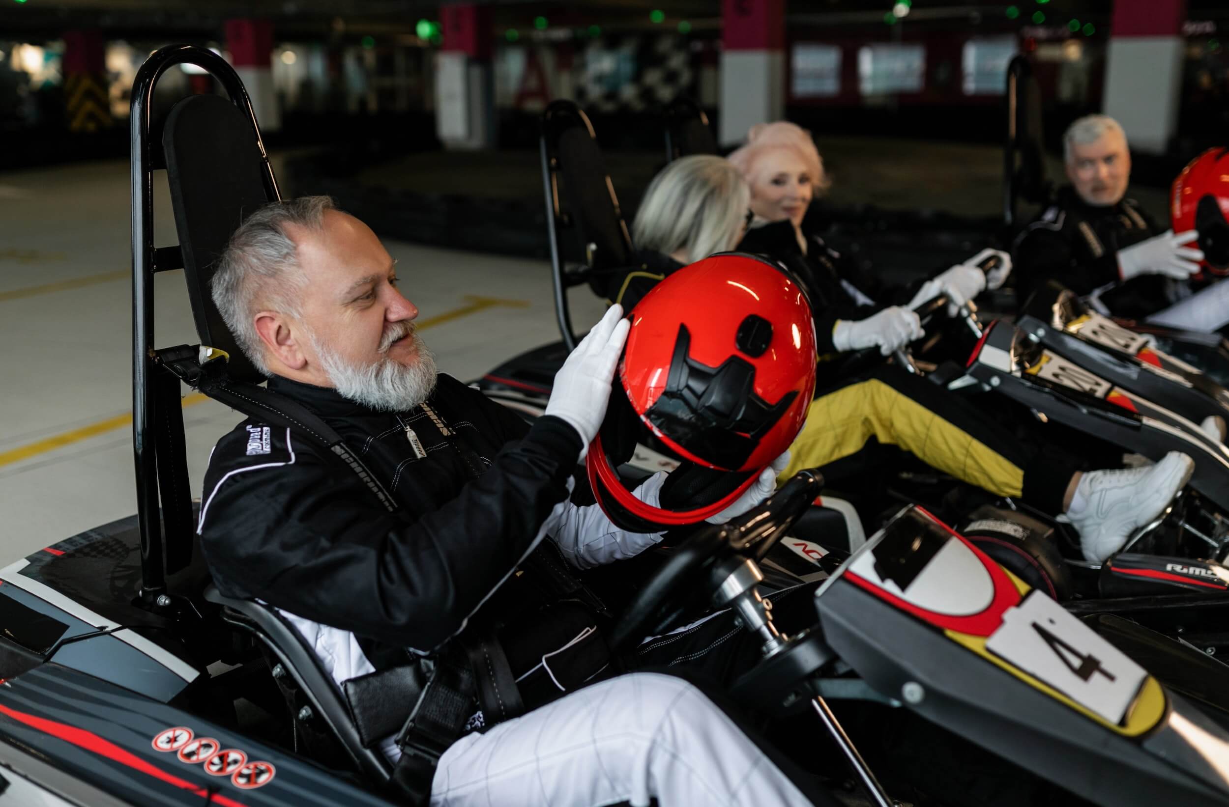Man with beard sitting in a go-kart putting on a helmet