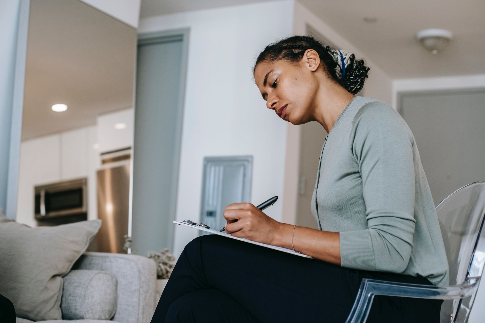 Woman taking notes on a clipboard while seated on a comfy chair