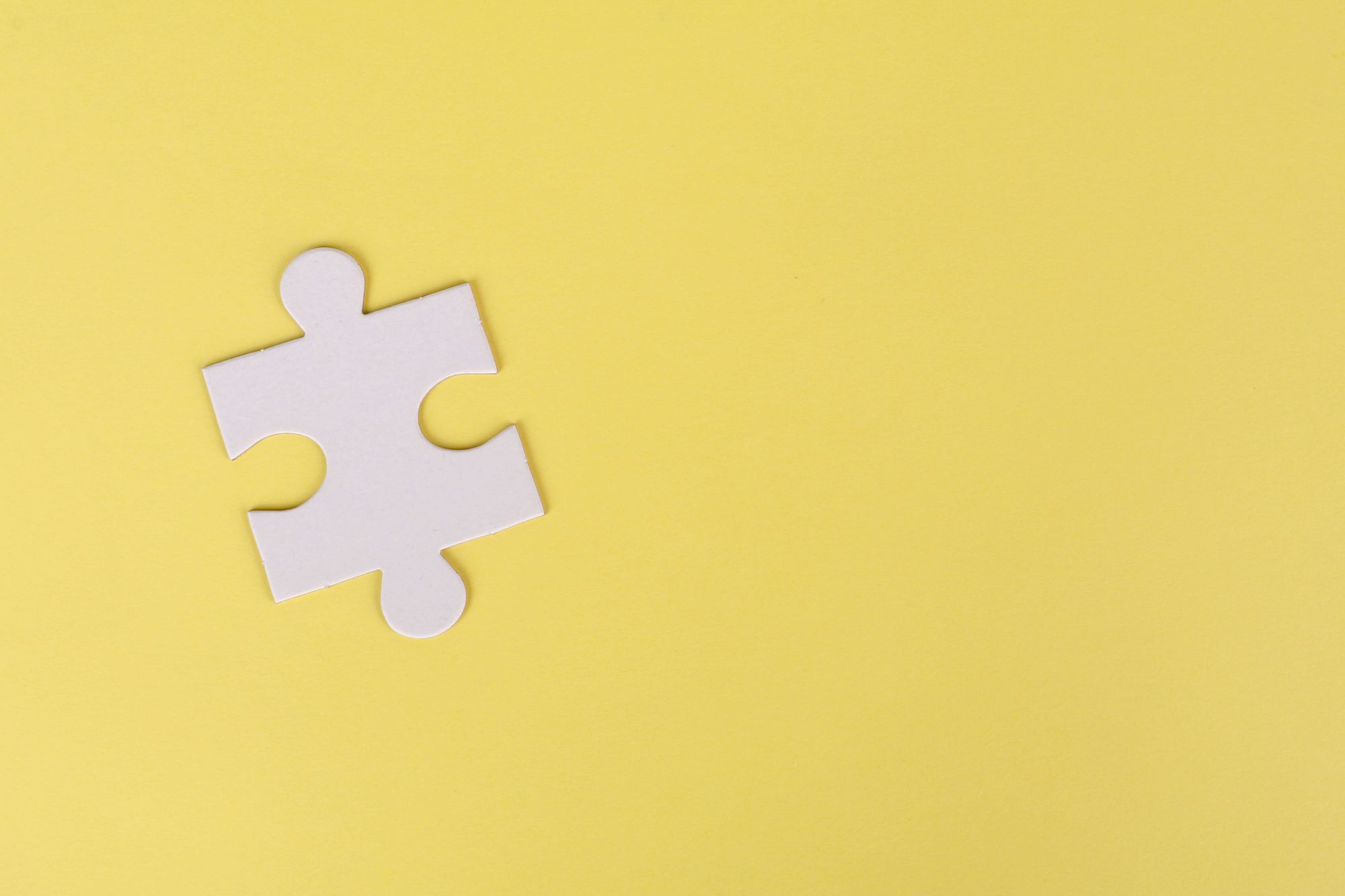 Photo of a white puzzle piece on a yellow surface