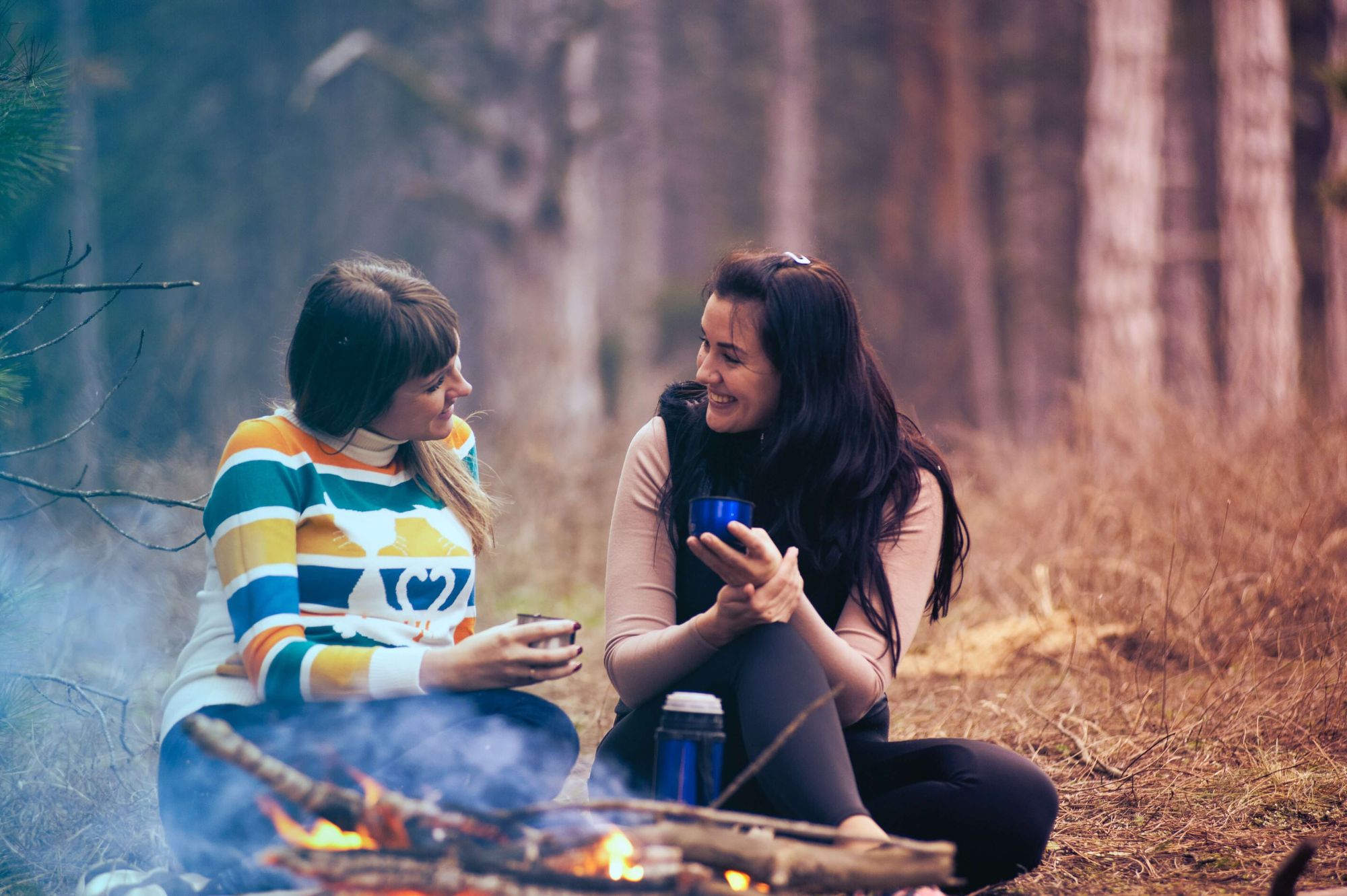 Photo of two women in conversation beside a camp fire