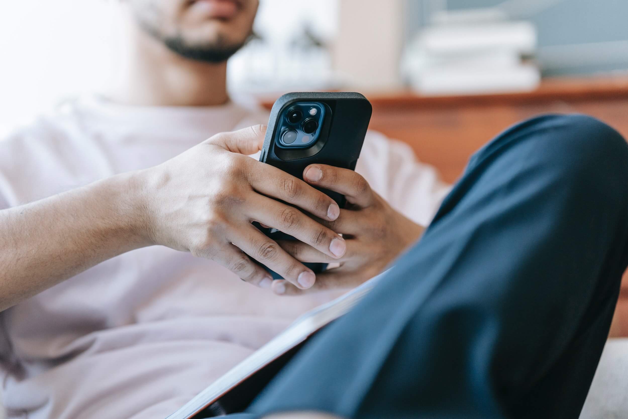 Photo of a man using a mobile phone while relaxing on a sofa