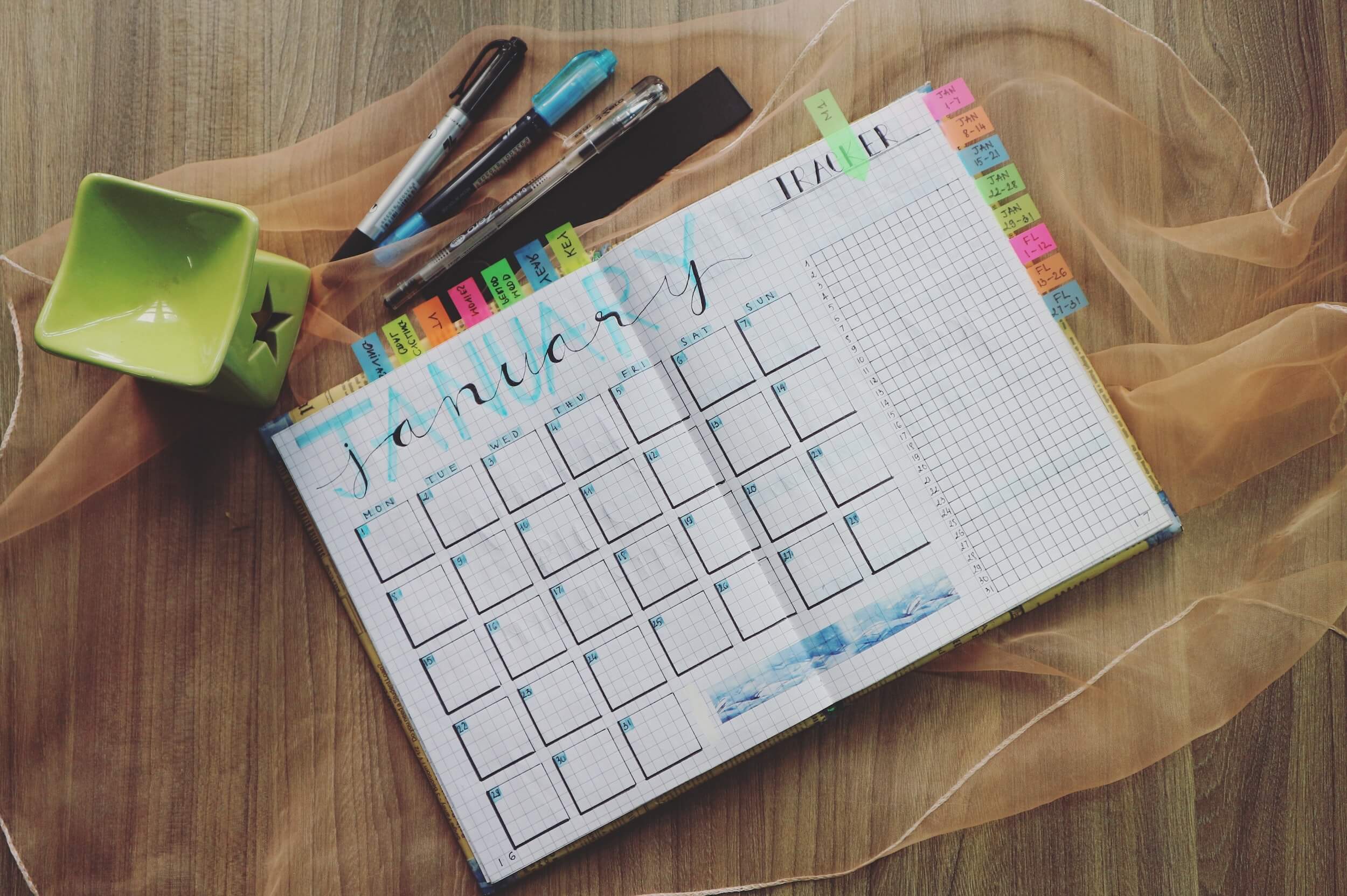 Year planner with coloured sticky tabs on a wooden desk 