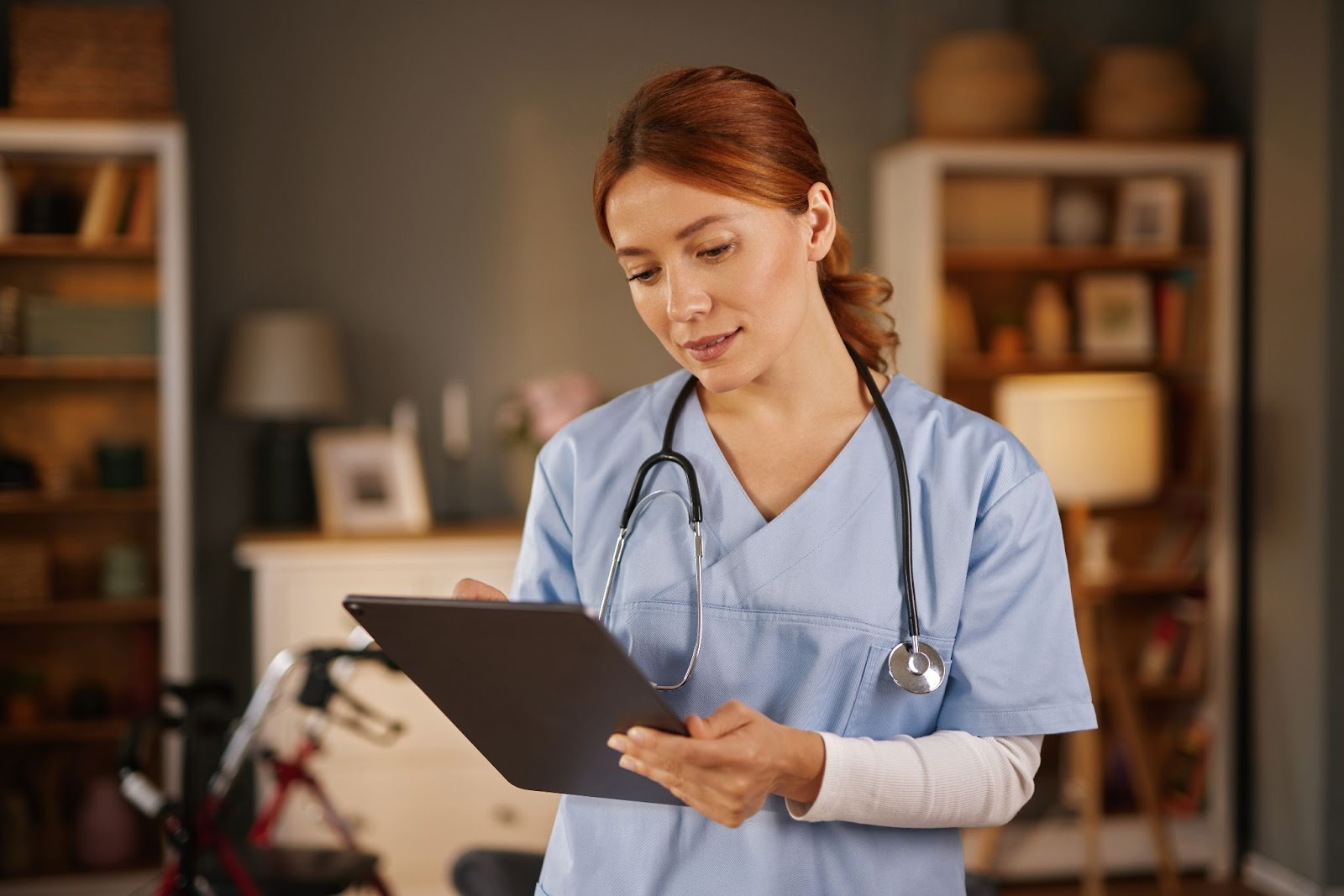 A healthcare professional in scrubs, writing notes on a clipboard.