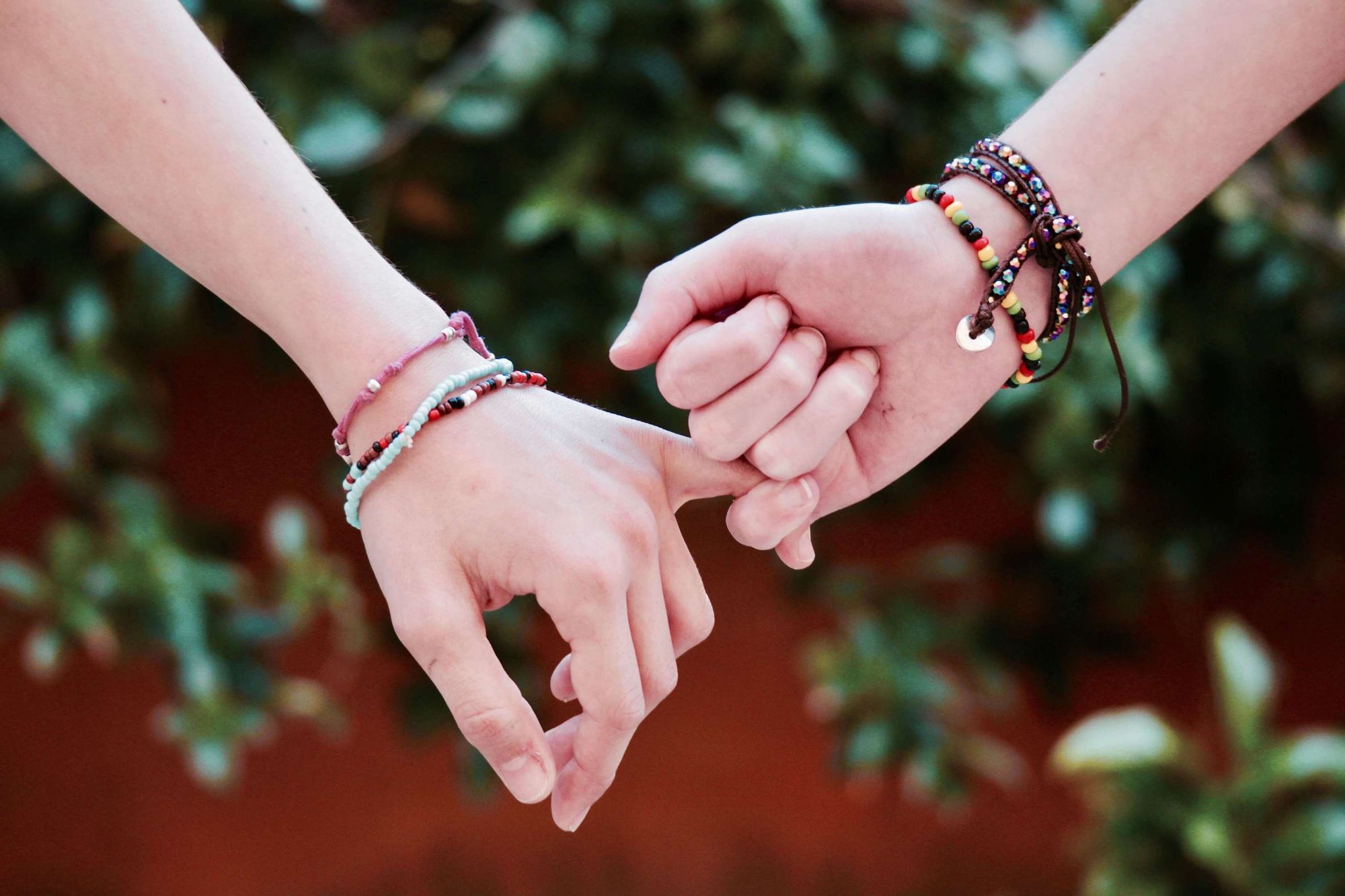 Close up of pair of interlocked hands against background foliage 