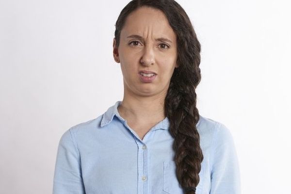 Confused-looking woman with long brown hair, wearing a light blue shirt