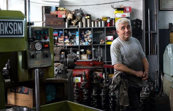 Man looking sidelong at the camera from inside his mechanic business
